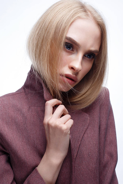 A young girl with long straight hair and nude makeup. Beautiful model in a pink coat. Blonde in a jacket. Beauty of the face - 写真・画像