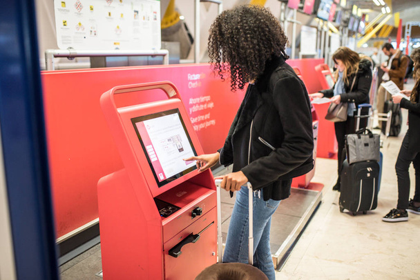mujer negra feliz usando la máquina de check-in en el aeropuerto conseguir la tarjeta de embarque
. - Foto, Imagen