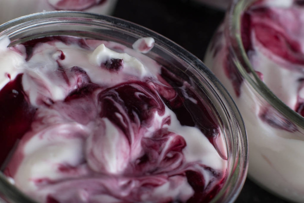Joghurts mit Früchteauswahl in Glasschalen auf dunklem Marmorhintergrund. Natur und Obst gesund, Ernährung, Gourmet-Dessert für Müsli-Frühstück. süße Joghurts Nahaufnahme - Foto, Bild