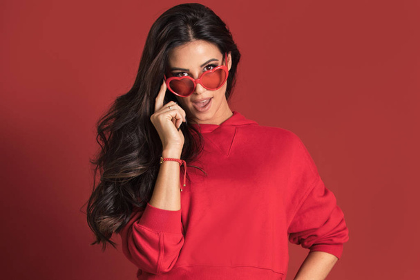 Fashionable beautiful woman posing on red background. - Photo, image