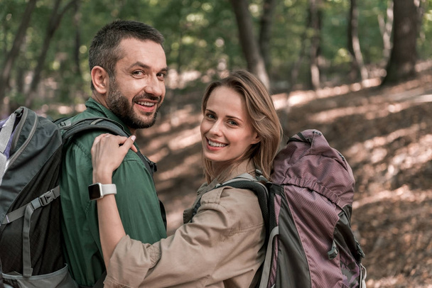 Homme et femme positifs profitant d'une promenade romantique dans la forêt
 - Photo, image