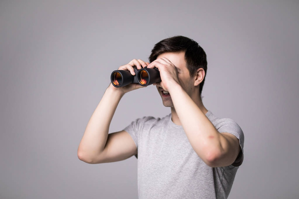 Young handsome man with binoculars isolated on white background - Foto, Imagem
