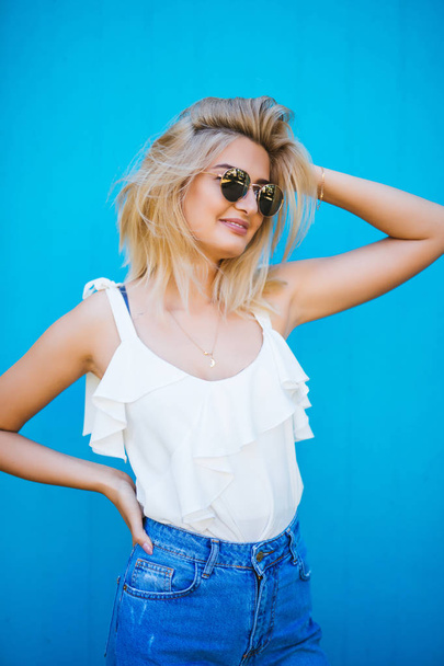 Portrait of funny emotional blonde girl on blue background - Foto, imagen