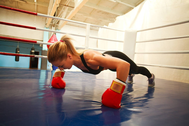 Sportovní mladá žena v Boxerské rukavice v tělocvičně dělat kliky v r - Fotografie, Obrázek