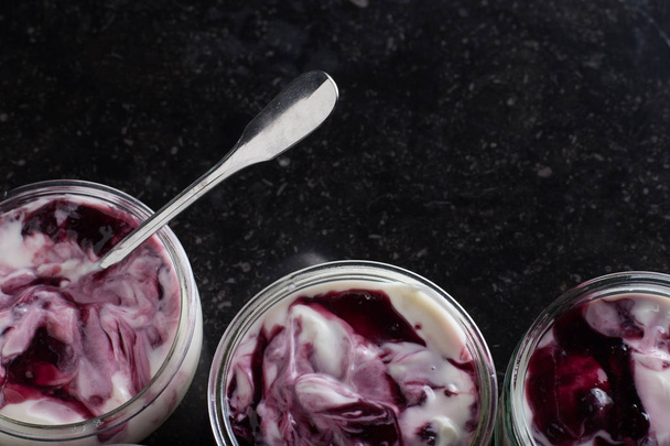 Йогурты с фруктовым ассортиментом в стеклянных мисках на темном мраморном фоне. Природные и фруктовые здоровые, диета, изысканный десерт на завтрак мюсли. Сладкий йогурт крупным планом
 - Фото, изображение