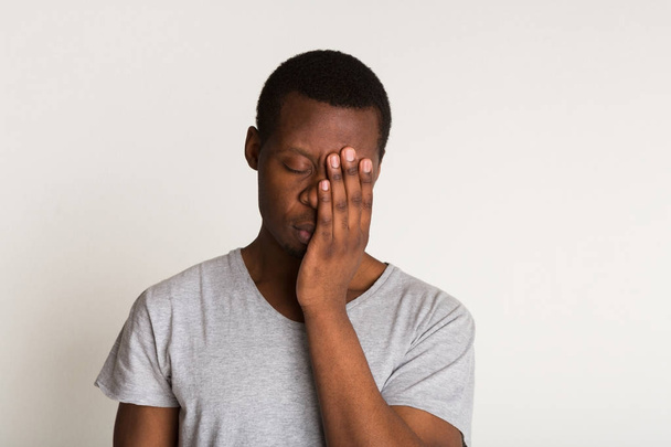 Tired young black man portrait. Hand covering face - Photo, Image