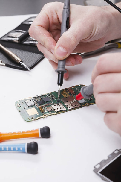 Repairing smartphone with multimeter close up - Foto, Bild