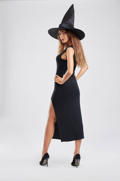 Pretty girl in a witch costume on a light background. Sexy witch in a hat. Halloween holiday concept. - Photo, Image
