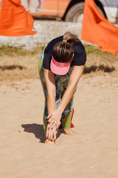 Tunnistamaton nainen venyttelemässä rannalla
 - Valokuva, kuva