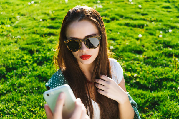 Woman doing selfie outside   on a grass ,copyspace  - 写真・画像