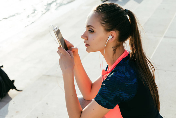 girl in sports uniform sits on the stairs looking in her phone - Foto, Imagem