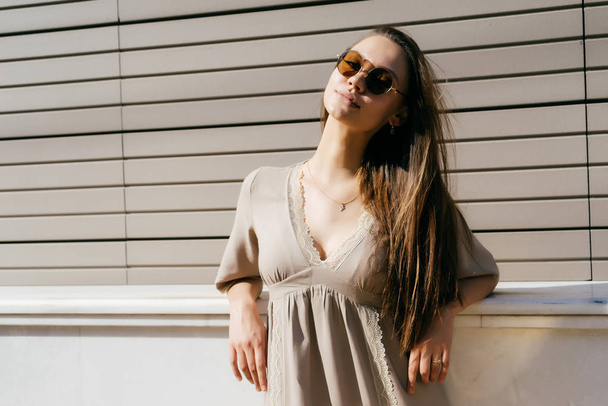 a girl in sunglasses leaned against a window sill on the street - 写真・画像