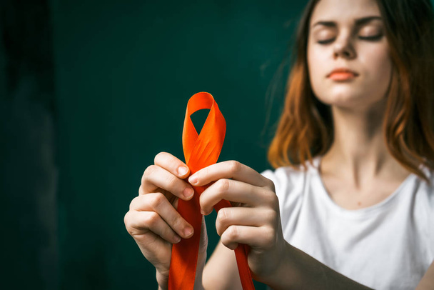 red-haired girl is standing with closed eyes holding an orange ribbon - Φωτογραφία, εικόνα