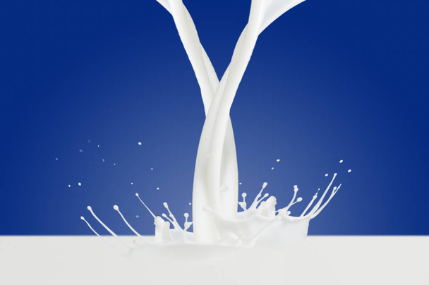 postříkání mléka na modrém pozadí - Fotografie, Obrázek