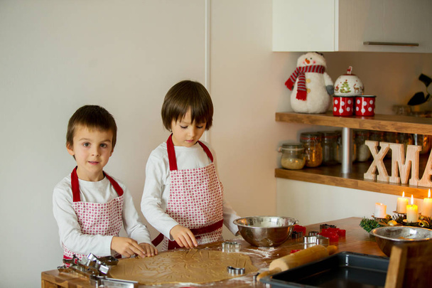 Two sweet children, boy brothers, preparing gingerbread cookies  - Valokuva, kuva