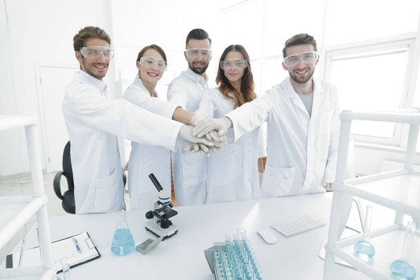 Menestyksekäs nuorten tiedemiesten ryhmä kädet yhteen kiedottuina
. - Valokuva, kuva