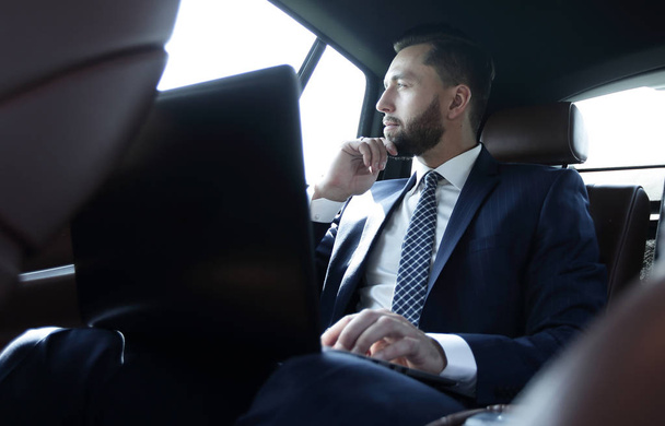 businessman working with laptop and looking out the window of a car - Foto, Bild
