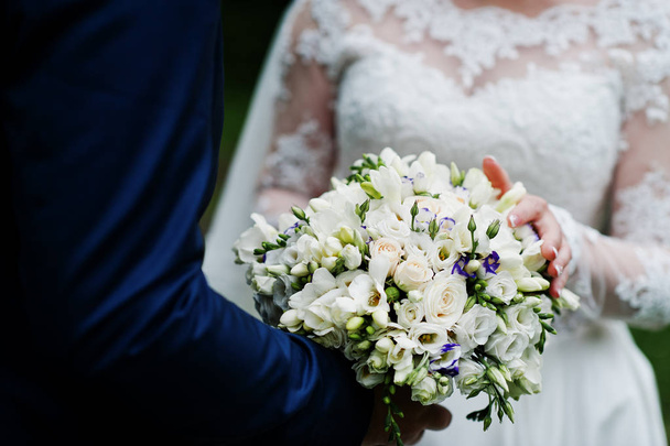 Close-up photo of a wedding bouquet in groom's hands. - Foto, afbeelding