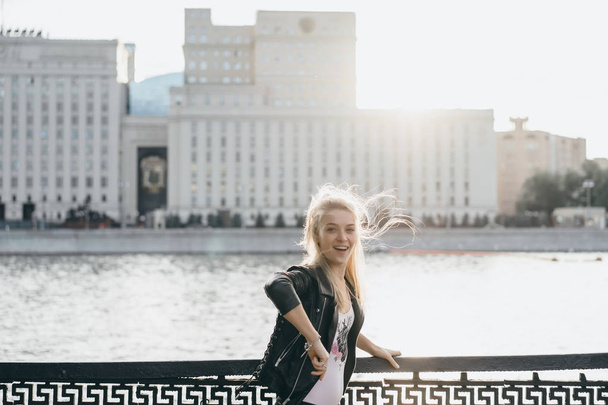 young blonde woman in black jacket on bridge outdoor - Foto, Imagen