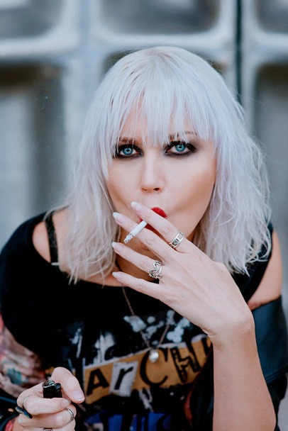 Portret van stijlvolle blonde grunge jonge vrouw roken sigaret - Foto, afbeelding