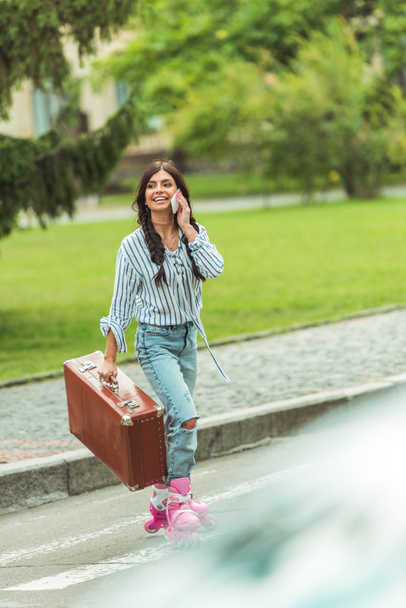 girl in roller skates with smartphone and suitcase - Foto, immagini