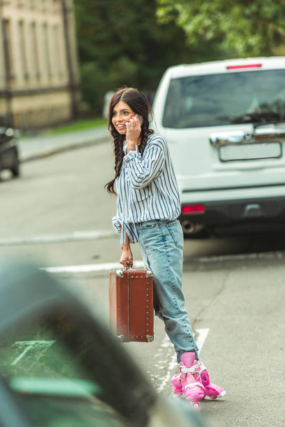 tyttö rullaluistimet älypuhelimella ja matkalaukku
 - Valokuva, kuva