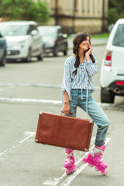 girl in roller skates with smartphone and suitcase - 写真・画像