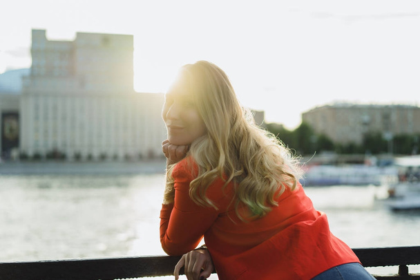 young blonde woman in red jacket outdoor at sunset time - Фото, изображение