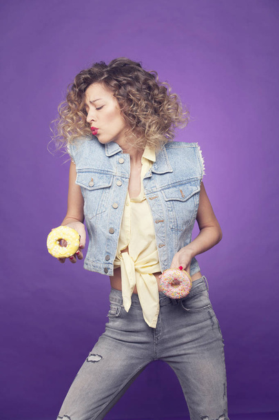 Curly girl posing with two donuts on purple background - Valokuva, kuva
