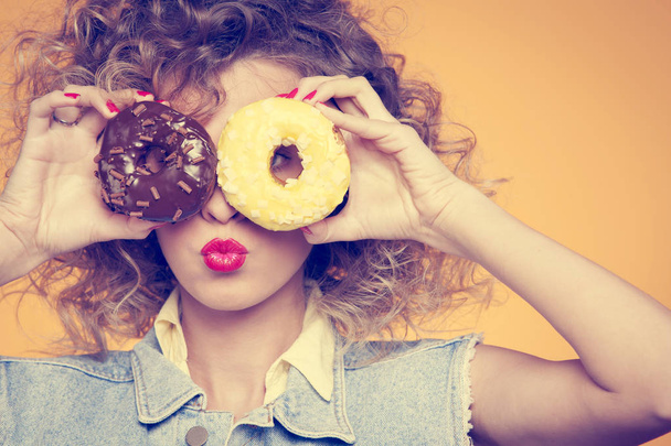 young woman put face to donut  - Foto, Bild