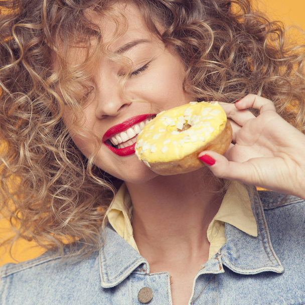 young woman put face to donut  - Foto, Imagem