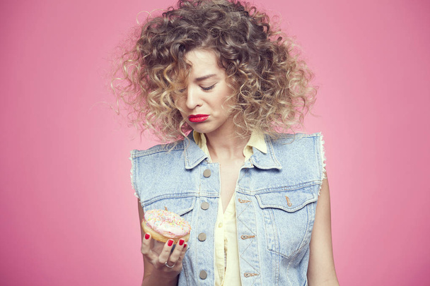young woman put face to donut  - Valokuva, kuva