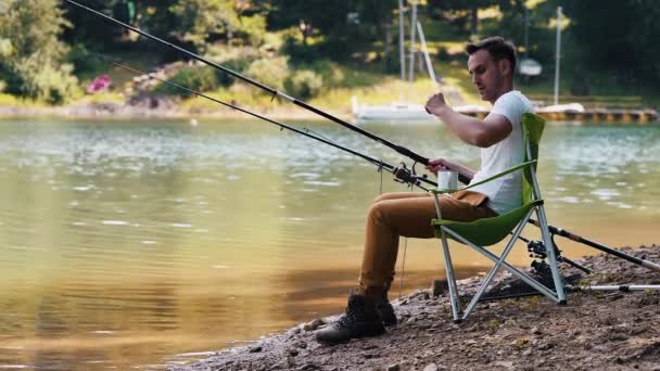 Muž sedí na židli rybolov a rybaření  - Záběry, video