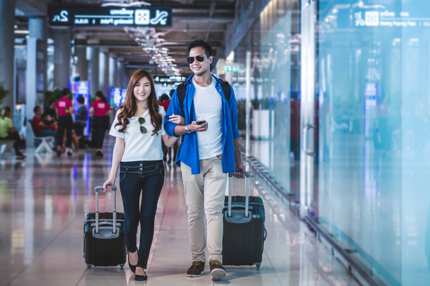 Aasialainen pari matkustajia kävely matkalaukut
  - Valokuva, kuva