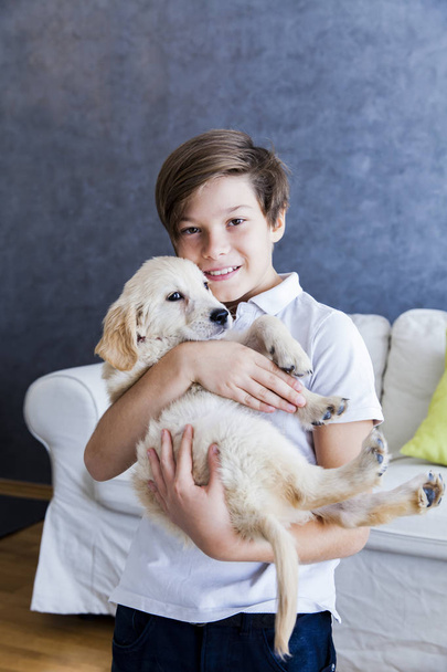 Cute teen boy with baby retriever dog in room - Photo, Image