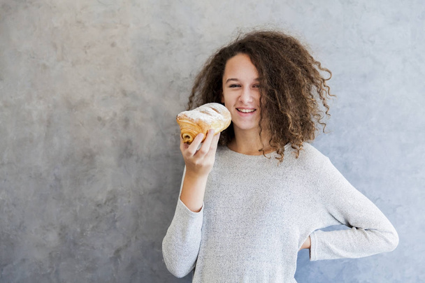 Cura cabelo encaracolado menina comer croissant
 - Foto, Imagem