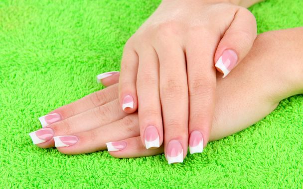 Woman hands with french manicure on green towel - Photo, Image