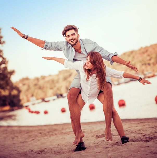 Casal fazendo piggyback na praia
 - Foto, Imagem