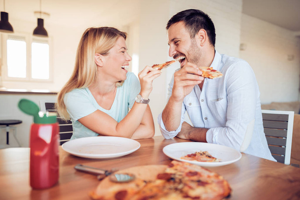 Couple eating pizza in living room. - Фото, изображение