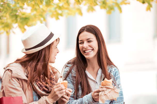 Meninas comendo sanduíches ao ar livre
 - Foto, Imagem