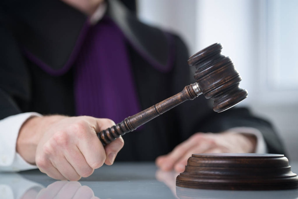 Концепция правосудия и права. Мужчина судья в зале суда с молотком и работающий с книгой
 - Фото, изображение