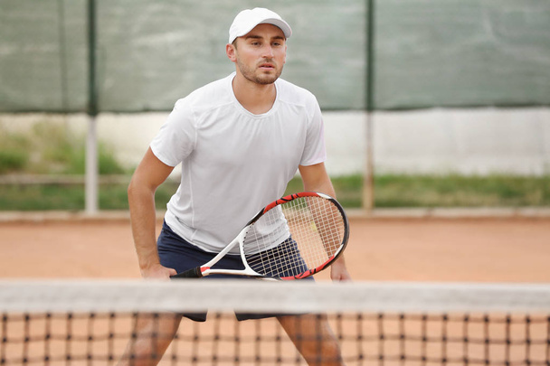 Молодий чоловік грає в теніс на корті
 - Фото, зображення