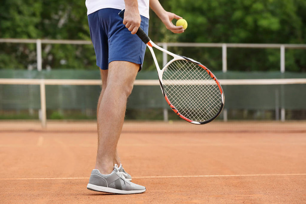 Young man playing tennis on court - Foto, afbeelding