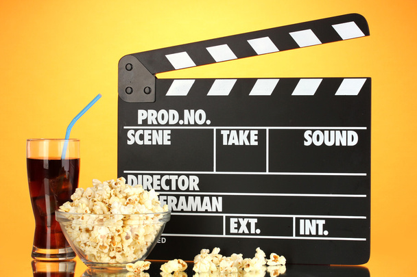 Movie clapperboard, cola and popcorn on orange background - Fotoğraf, Görsel
