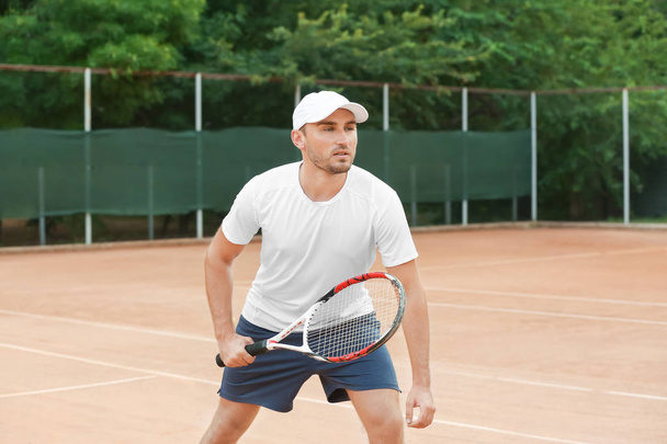 Young man playing tennis on court - Zdjęcie, obraz