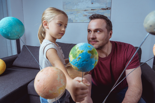 Girl showing father model of Earth   - Zdjęcie, obraz