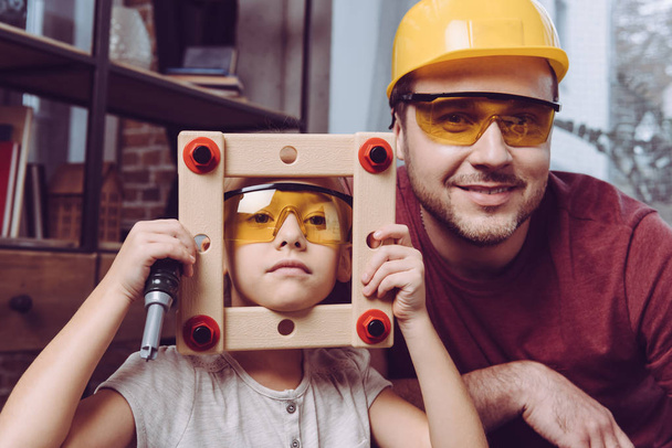 Vater und Tochter posieren mit selbst gebasteltem Rahmen  - Foto, Bild
