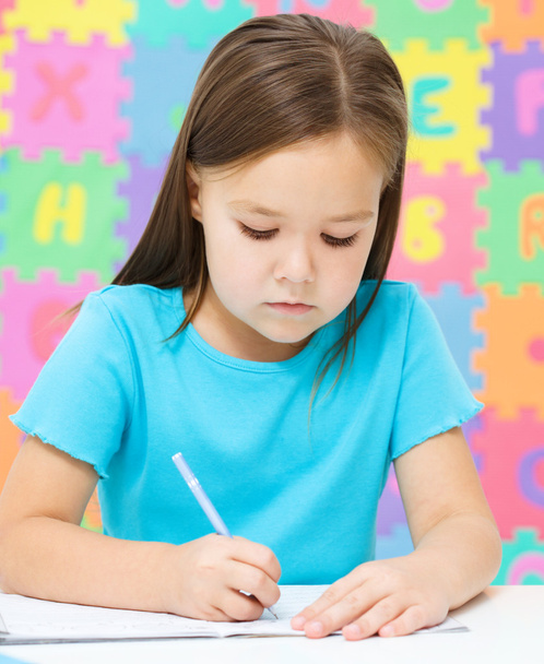 Little girl is writing using a pen - Foto, Imagen