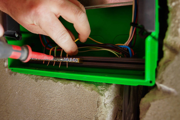 Manos cableado eléctrico se tira a través del agujero en la pared de los paneles de yeso
. - Foto, imagen