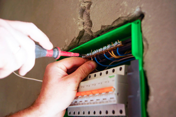 Mãos fiação elétrica é puxada através do buraco na parede do drywall
. - Foto, Imagem